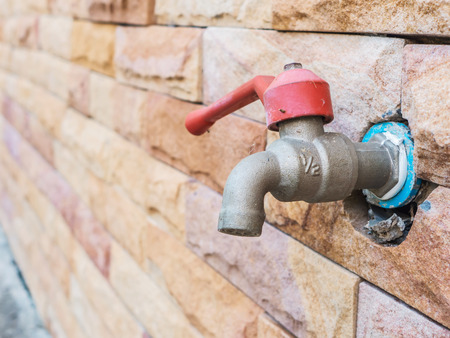 Dirty water tap on stone brick wallの写真素材