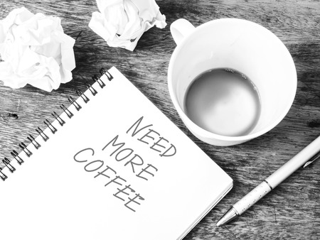 Empty cup of coffee ,crumpled paper and notepad with text, black and white colorの写真素材