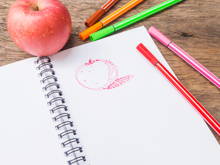 Apple and drawing sketch on notepad on wooden desk,top viewの写真素材