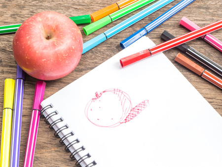 Apple and drawing sketch on notepad on wooden desk,top viewの写真素材
