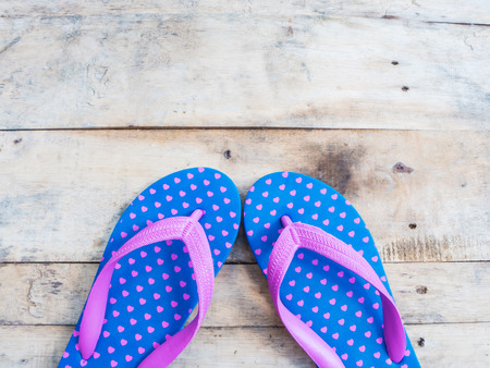Blue flip flop with pink heart pattern on wood backgroundの写真素材