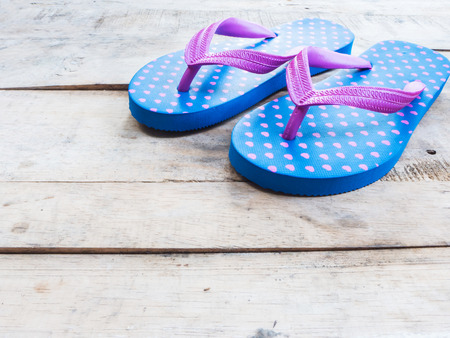 Blue flip flop with pink heart pattern on wood backgroundの写真素材
