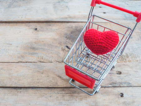 crochet heart in shopping cart on wood backgroundの写真素材