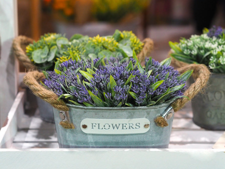 Artificial flowers in flowerpots on shelf for interior decoration.