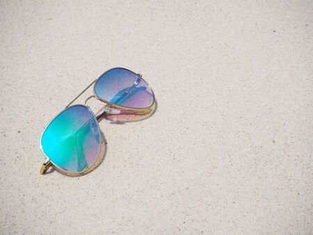 Fashionable mirror sunglasses on sand beach backgroundの写真素材