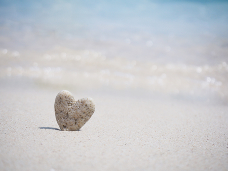 Stone heart shape standing on summer beach sand, love concept.の写真素材