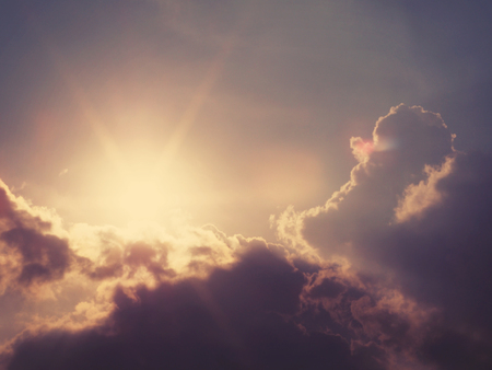 Abstract blurry nature background of sun behind grey clouds with soft style, vintage filter effectの写真素材