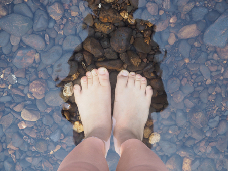 Selfie bare feet on the stones in the water, top view.の写真素材