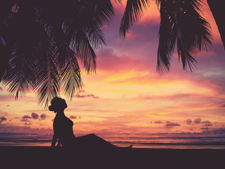 Silhouette Of woman and palm tree on sunset beach, vintage filter effect.の写真素材