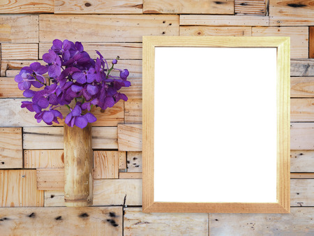 Violet vanda orchid in bamboo vase and blank picture frame hanging on wooden plank wall. Shabby vintage interior style.の写真素材