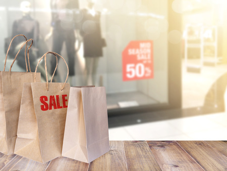 Set of shopping bags with wording SALE on wooden table over blurry background of fashion window display at department store. Black Friday concept.の写真素材
