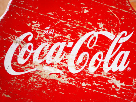 PRACHINBURI, THAILAND 2018 - January 21, 2018: Close up white Coca-Cola brand on vintage red wood stool at Yusuksuwan Museum, Prachinburi province, Thailand.のeditorial素材