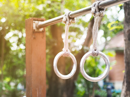 Close up metal rings with strings on exercise bar with sunlight morning at outdoors gym in the park.