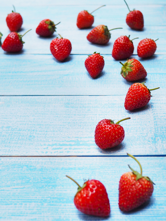 Set of red strawberries on blue wooden background. Juicy fruit.の写真素材