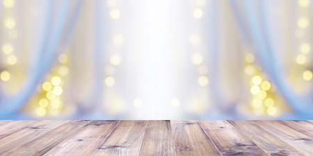wood table tiop over abstract blur background of white curtain with light bulb bokeh at window in bedroom. Banner background with copy space. Montage style.の写真素材