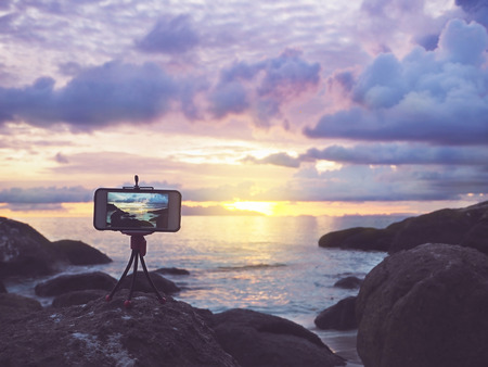 Close up smartphone on stand mobile tripod take sunset landscape photo and video timelapse at summer beach.
の写真素材