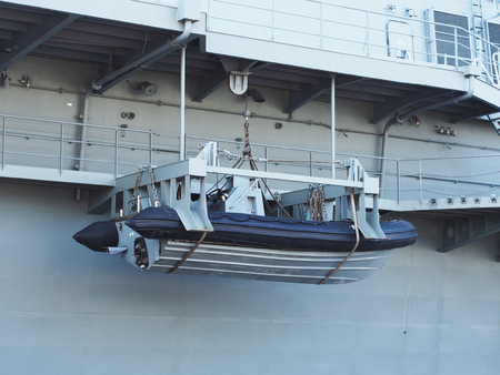 Lifeboat hanging in the air on the side of warship.