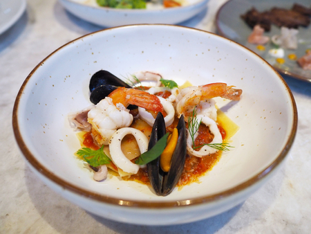 Close up lasagna with seafood and spisy sauce on top in white plate. Fusion Italian food.の写真素材