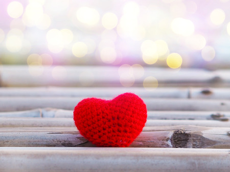 Close up red cushion heart shape on bamboo wood with bokeh and copy space for valentines background. Love concept.の写真素材