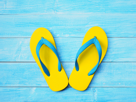 Top view of yellow rubber flip flop shoes on blue wooden background with copy space. Summer holiday vacation concept.の販売画像