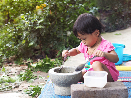 Asian girl kids play cooking papaya salad with mortar in the garden.の写真素材