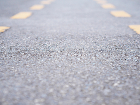Perspective asphalt street surface with yellow line. Close up concrete road texture and background.