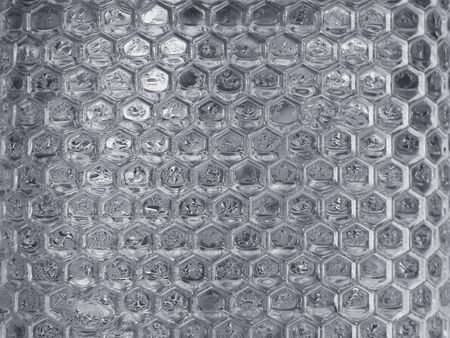 Close up hexagon shape pattern of transparent glass wall background with water drops.