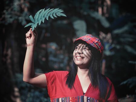 Smiling Asian woman hand holding fern leaf sunshade in the green tropical forest background, vintage filter effectの写真素材