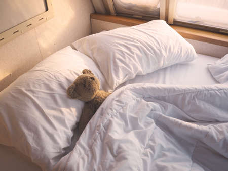 Brown teddy bear on bed at mobile car bedroom in the morning.の写真素材