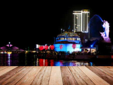 Wooden table top over abstract blur background of Da Nang night by Han river with carp dragon....