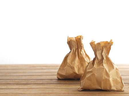 Close up brown recycle paper bag on wooden table over white background.の写真素材