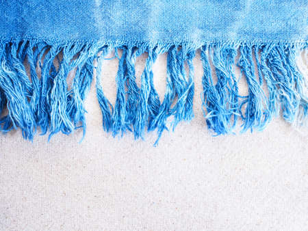 Close up indigo tie-dye fringe edge on beige cotton fabric texture. Natural vintage textile background.の写真素材