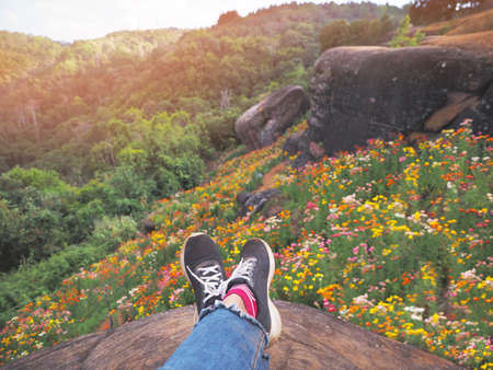 Selfie hipster wearing black sneaker shoes over wild flower field background at viewpoint on mountain. Relaxation on vacation holidays concept.の写真素材
