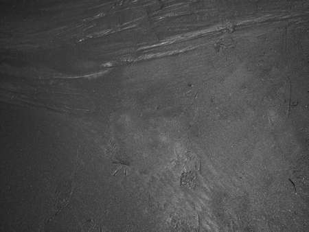 Top view of black sand with rippled on summer beach texture background.