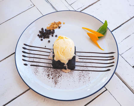 Close up vanilla scoop ice cream and beownie cake over chocolate sauce decorated on white plate.の写真素材