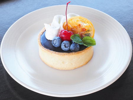 Close up small cake with fruit and whipping cream on white plate. Bakery cupcake.の写真素材