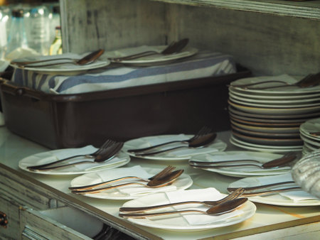 Empty white plates with spoons and forks preparration at hotel. Set of dishes on the table for party.の写真素材