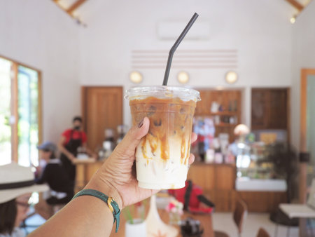 Selfie hand holding glass of iced coffee in coffee shop.の写真素材