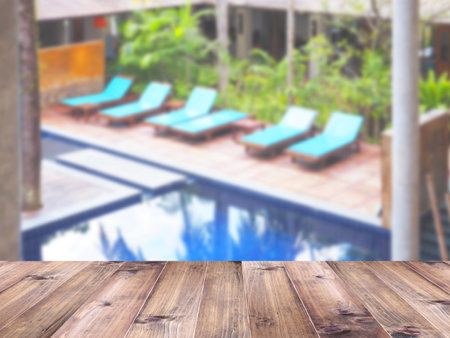 Wooden table top over blurry swimmimg pool background. Montage style to display the product.の写真素材