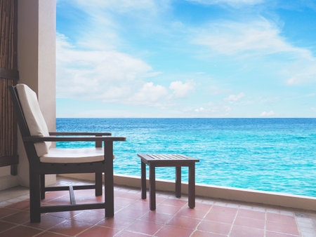 Vintage chair and coffee table on balcony in front of resort over summer beach background. Happy holiday and relaxation conceptの写真素材