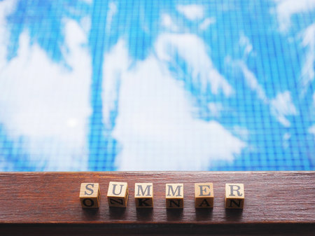 Close up wooden block text Summer on wooden board over swimming pool background with copy space. Happy holiday concept.の写真素材