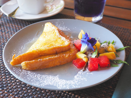 Close up honey bread toasted with icing sugar on top and fruit salad for breakfast.