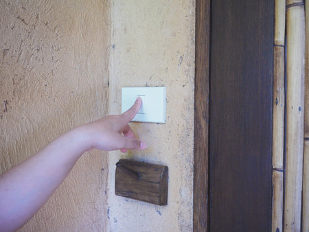 Woman pushing door bell. Close up finger touching switch button in entryway of building.