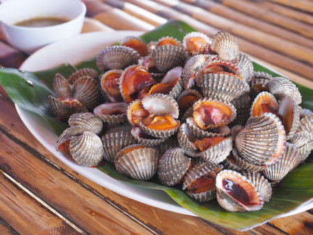 Steamed cockle or Boiled cockles served on green banana leaf background. Seafood food.の写真素材