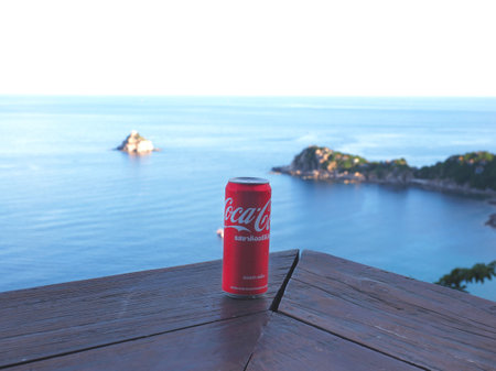 Koh Tao island, Thailand - July 22, 2022: Close up red can of Coca-Cola soft drink on wooden table...