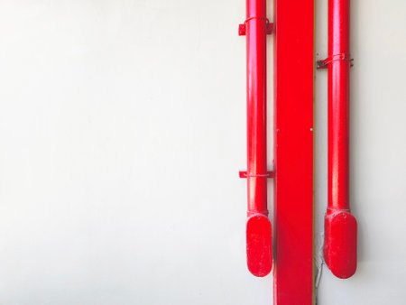 Close up red metal standpipe on white concrete background. Industrial pipe over factory wall with copy space.の写真素材