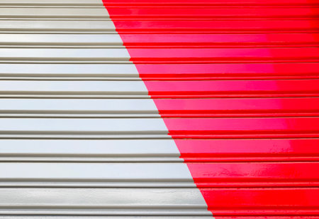 Closed up painted corrugated metal door backround. Red and grey color paint on rolling shutter door.
