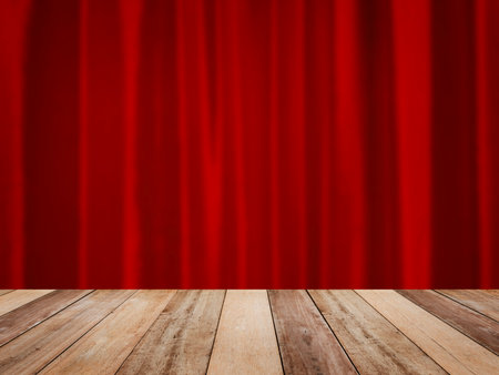 Wooden table top over abstract blurry red velvet curtain on stage. Christmas or Chinese new year background.の写真素材