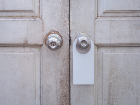 Blank white hanger hanging at metal knob of vintage wooden door.の写真素材