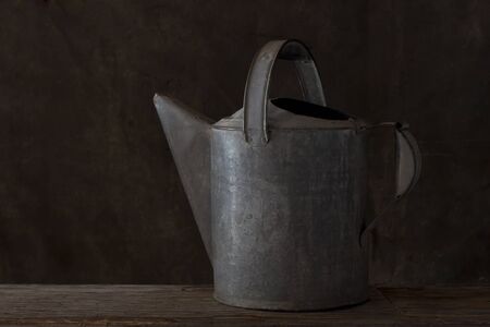 Still life of rustic old watering can on an old wooden plank.の写真素材